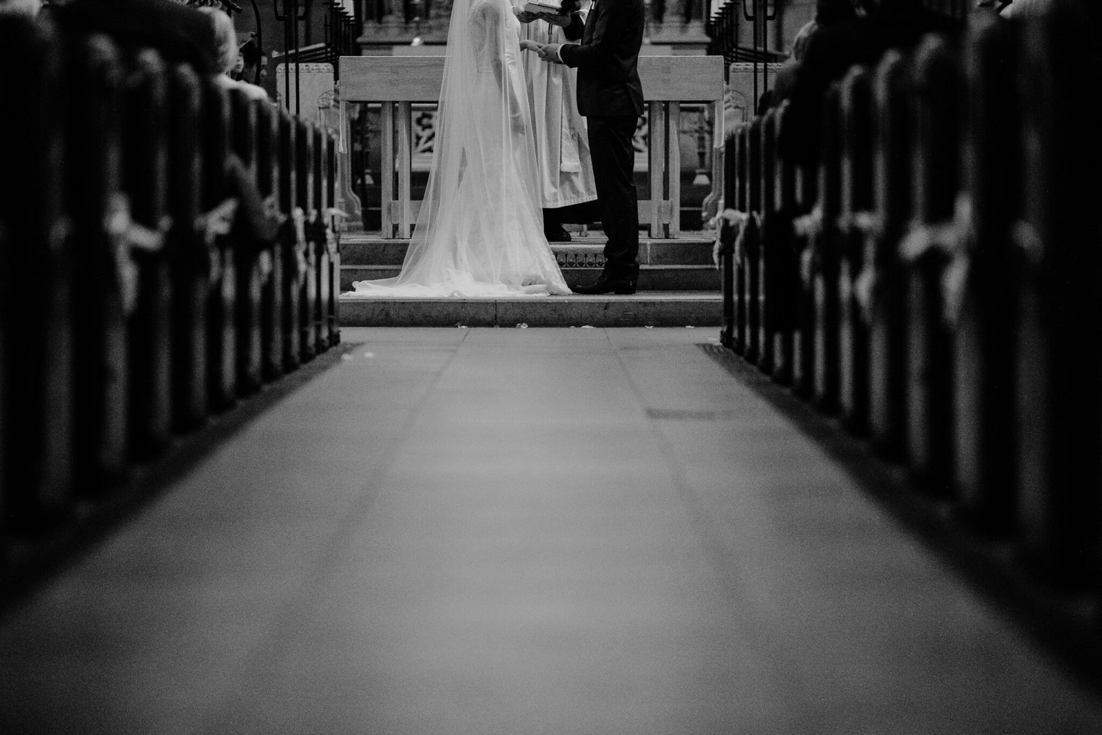 Black and white view down a church aisle toward the altar