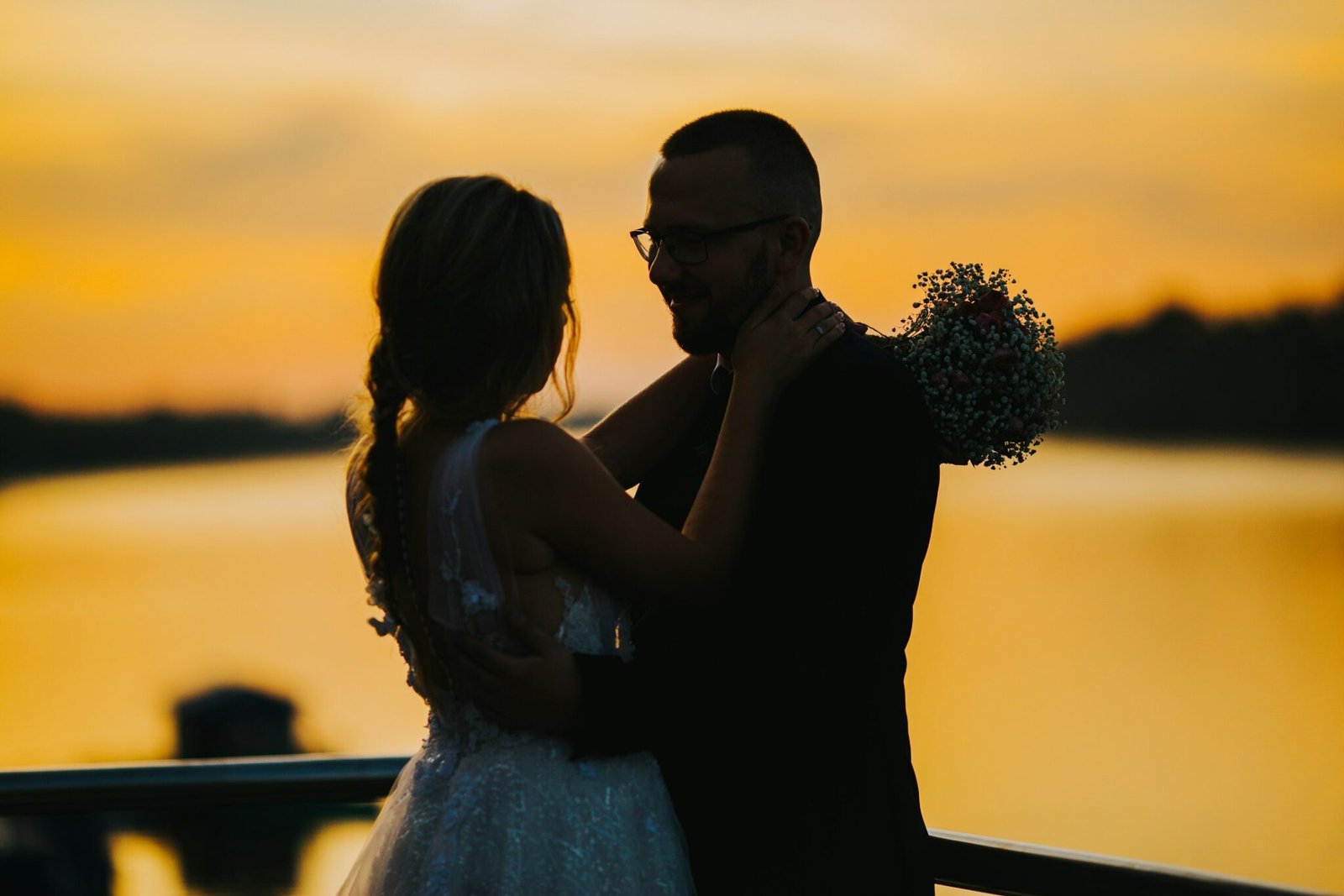Couple embracing in silhouette by the water at sunset