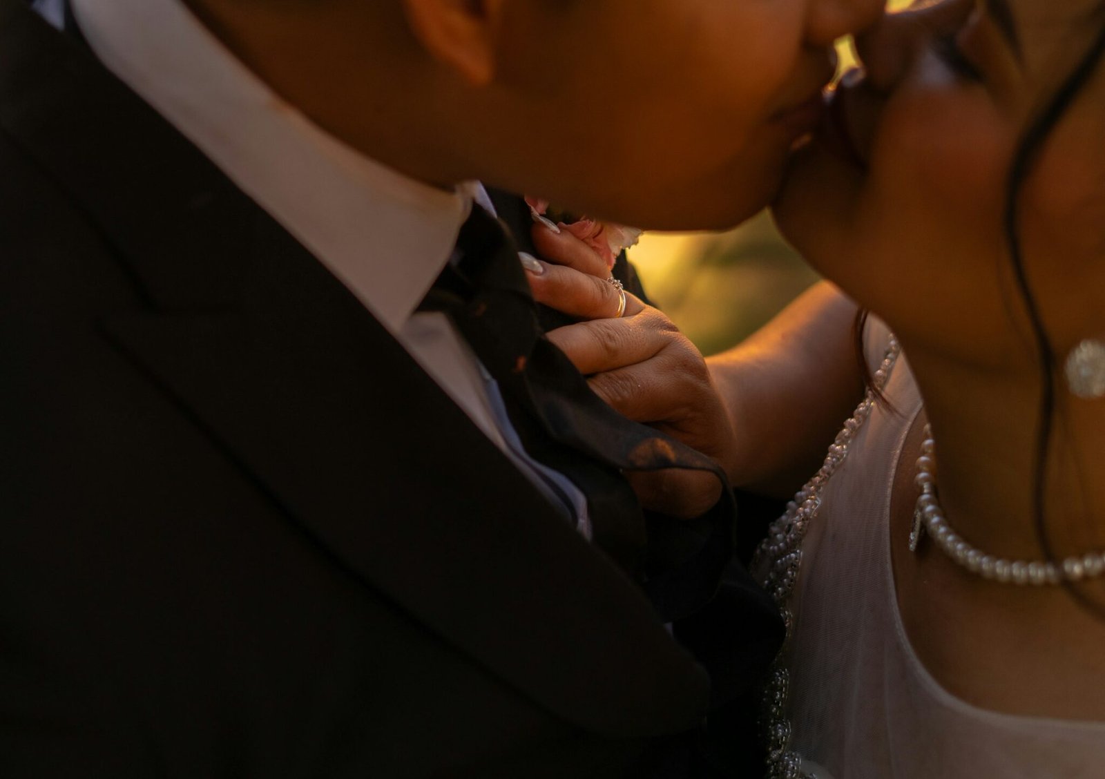 Bride and groom sharing a tender kiss in low warm light