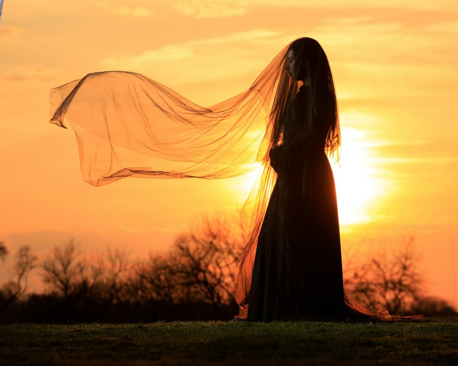 Bride silhouetted against an orange sunset sky