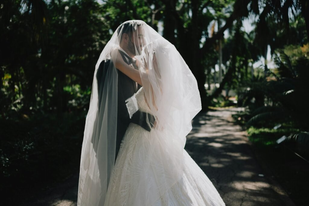 Bride and groom embracing under her veil among trees